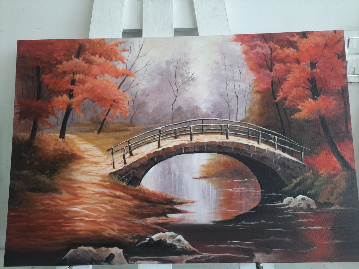 A stone footbridge over a still stream between red and orange autumn trees, with mist behind.