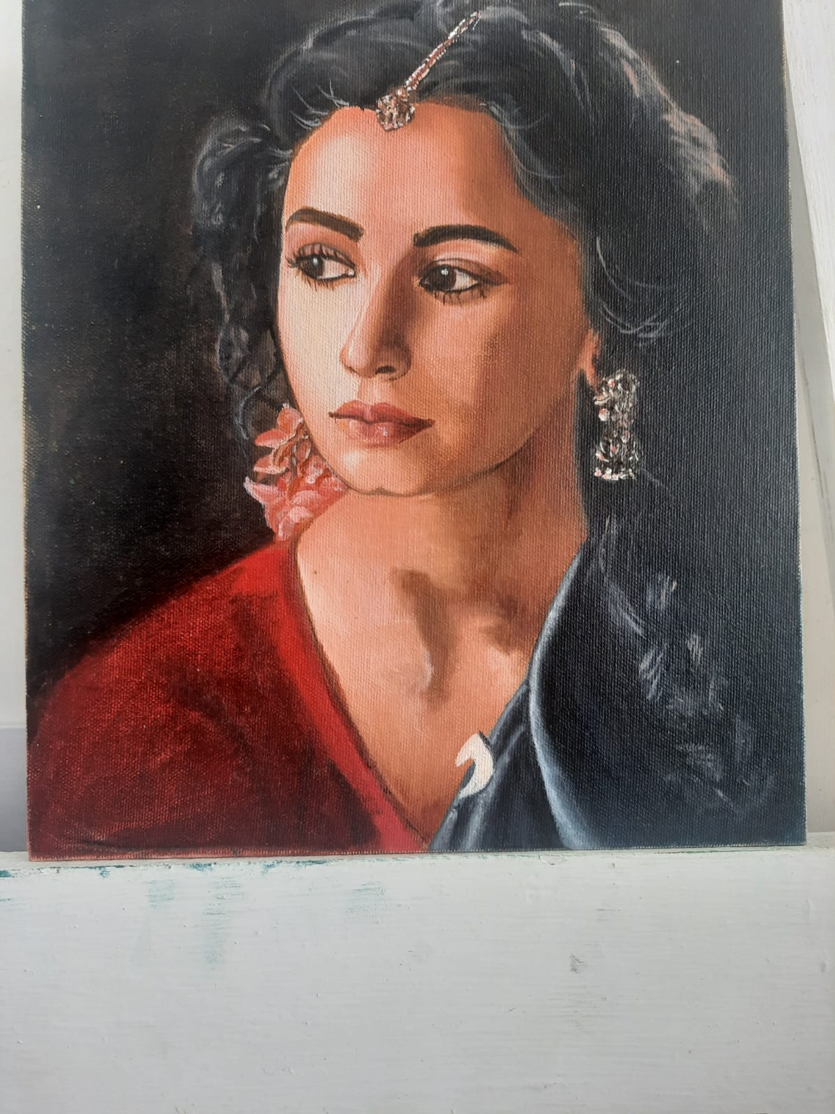 Oil portrait of a woman in a red blouse and dark dupatta, with a maang tikka and pink flowers in her hair.