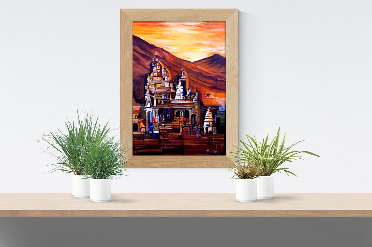 A painting of a carved stone temple glowing against dark hills under an orange sky, shown in a wooden frame on a wall.