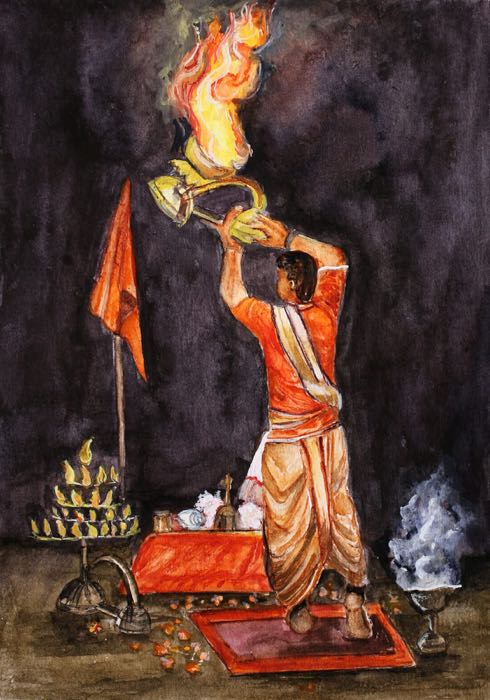A priest in saffron raising a blazing brass lamp at the evening aarti, against a night-dark sky.